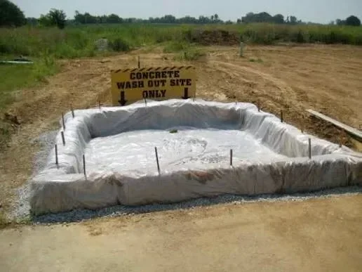 A concrete washout containment unit positioned on an active construction site in Charlotte, NC, with dried concrete residue collected inside the lined container. A concrete truck chute is angled toward the washout area after a pour.
