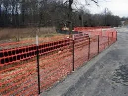 Safety fence installed around a freshly seeded and straw-covered slope on a residential construction site in Charlotte, NC. Orange mesh fencing marks the perimeter of the seeded area to protect new ground cover from foot traffic and equipment.